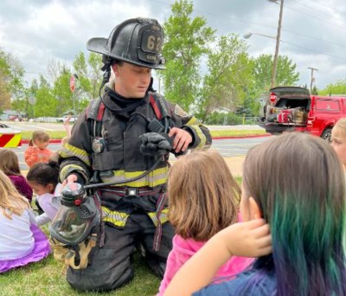 Firefighter showing school age children his bunker gear